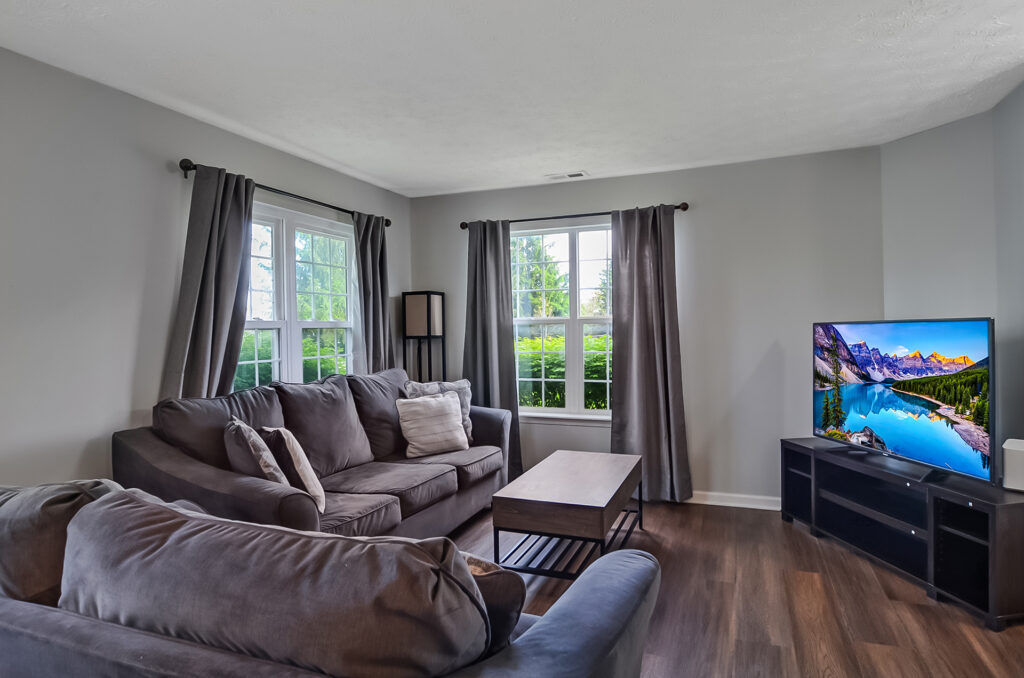 Cozy living room with large windows and grey sectional sofa at Property 4