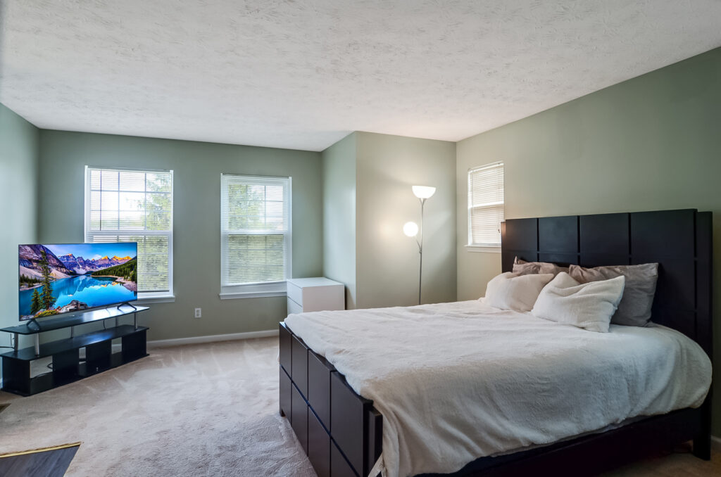 Bright bedroom with large windows and queen-sized bed